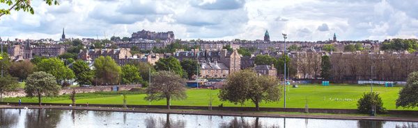 a view over a boating pond towards a city skyline
