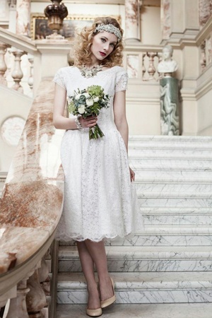 a bride in her wedding dress stands on a marble staircase holding a bouquet of flowers