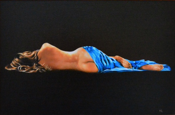 a young semi-naked woman with long brunette hair lies on her side with her bottom half covered in a blue silk sheet