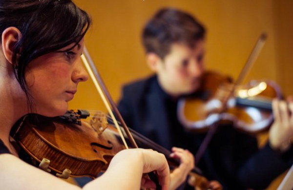 a man and woman sit playing the violin