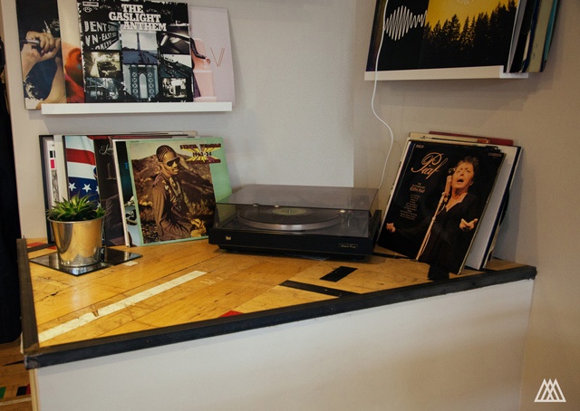 a vinyl record player sits on a shelf next to piles of records