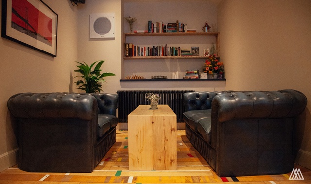 Two Chesterfield sofas with a wooden table between them face each other in the corner alcove of a wine bar