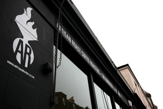 the black exterior of a coffee shop looking up to a cloudy sky