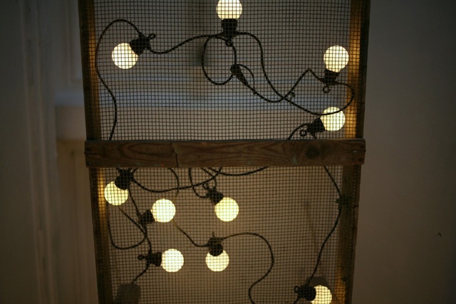 a string of lights lie on a mesh covered frame