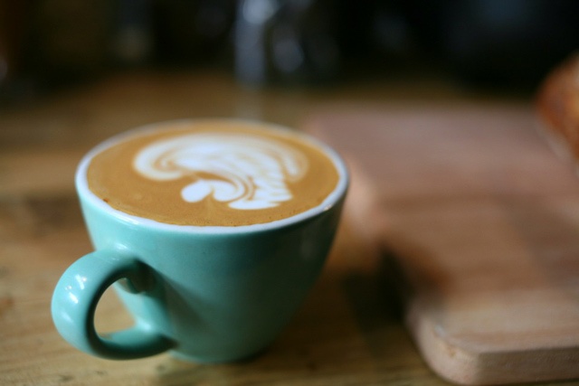 a small green cup of coffee on a wooden counter