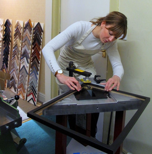 a woman makes a picture frame for a painting at Netherton Framing in Stockbridge, Edinburgh