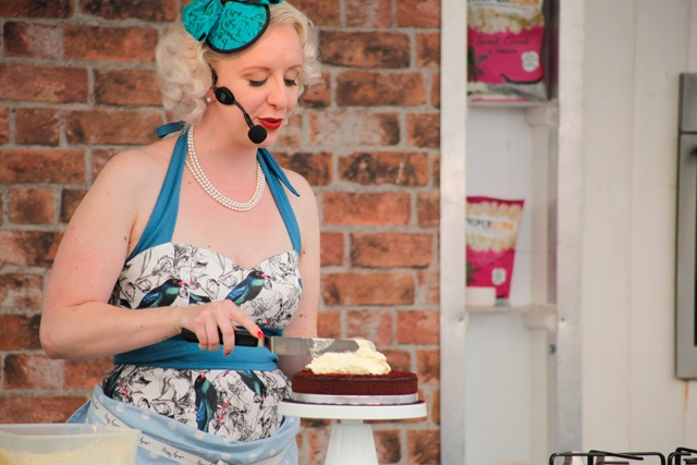 a woman stands icing a cake