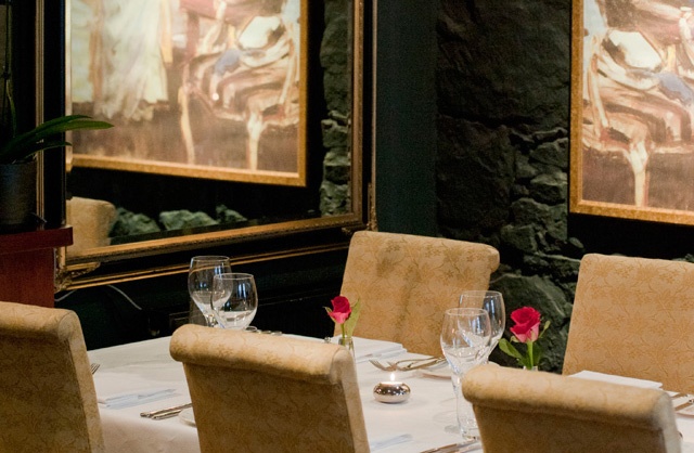 a restaurant table covered in white linen set with cutlery and glasses
