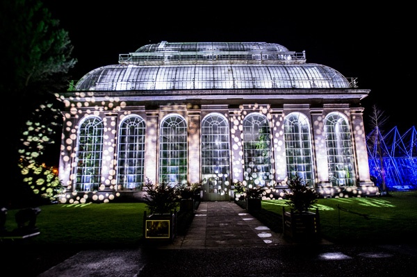 Old victorian botanical glasshouse illuminated in crisp white festive lights at night