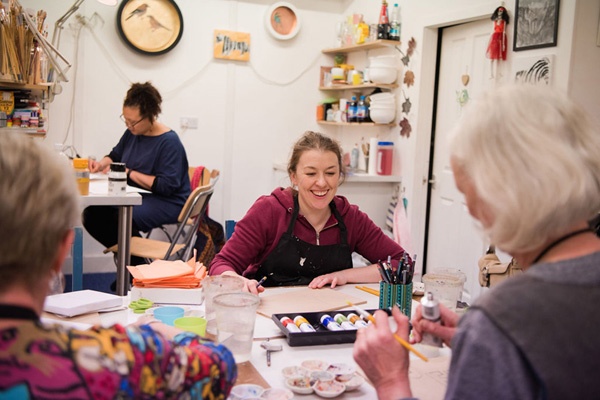 four women paint in an art class