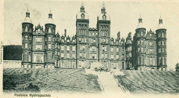 old stone building with six turrets sits on a hill with steps leading up to it