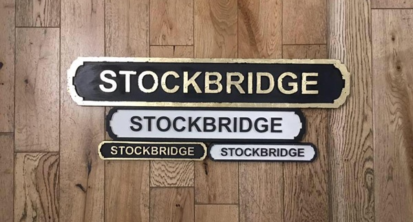 gold on black and black on white Stockbridge street signs lying on a wooden floor