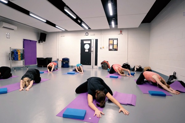 seven women lie on the floor in various yoga poses