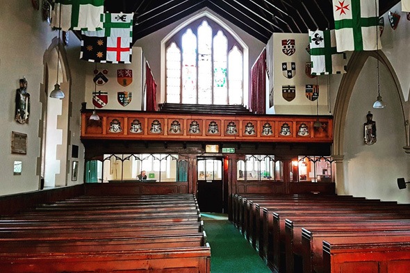 inside an old stone chapel with wooden pews on each side of the isle