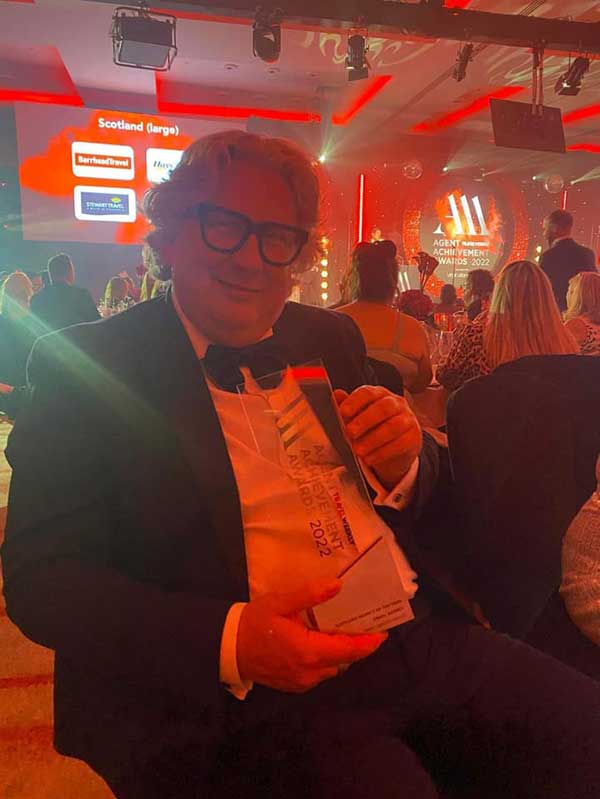 Jimmy Martin wearing a tuxedo holding the award for Best Travel Agent in Scotland