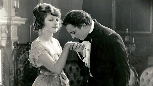 a man meets a woman and bows to kiss her hand