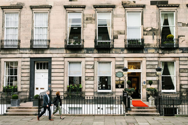 The exterior of the Nira Caledonia Hotel in Edinburgh. A long Georgian terrace lined with black iron railings and window boxes.