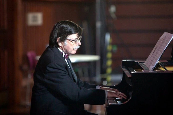 Pianist Derek Clark sits playing the piano for Opera Caledonia
