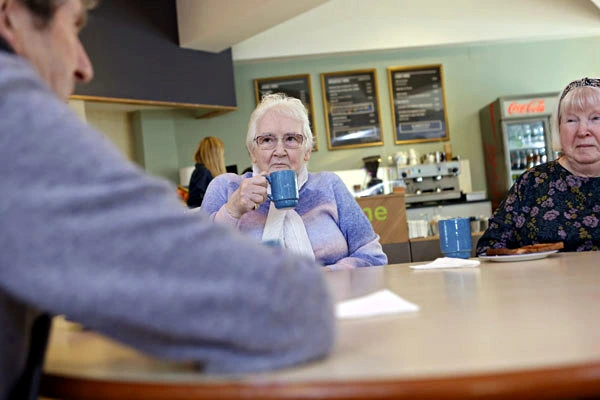 A group of people sit at a table in a cafe at charity organisation Lifecare in Edinburgh