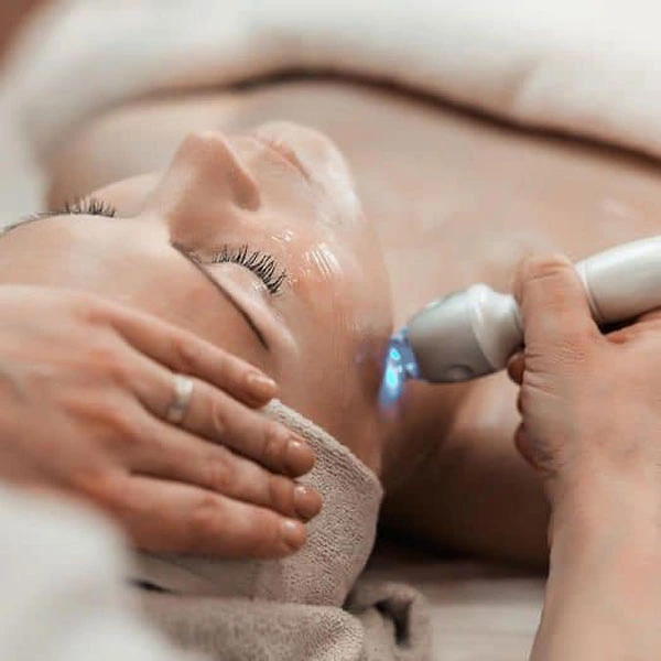 A woman lying on a table wrapped in a white towel receiving an electrolysis treatment at Fior Health and Beauty in Stockbridge, Edinburgh